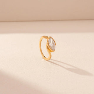 Angled view of a 14KT yellow gold ring featuring a marquise-cut diamond in a bezel setting, set against a beige background.