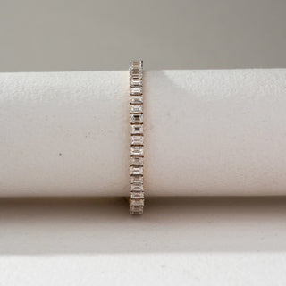 Front view of Emerald Cut Diamond Tennis Bracelet in 14KT Dual Gold, featuring a continuous row of emerald-cut lab grown diamonds in prong setting. Set on a beige backdrop, the design highlights symmetry and brilliance.
