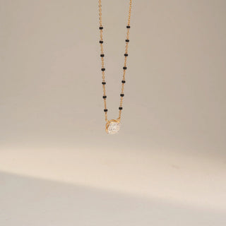 Angled view of a yellow gold lab-grown diamond mangalsutra featuring a round solitaire diamond pendant in a modern open-frame setting on a delicate black bead chain, displayed on a neutral background.
