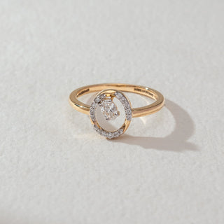 Top view of oval halo diamond ring in yellow gold, featuring a centred oval lab-grown diamond within an open oval frame lined with round diamonds. Set on a soft neutral surface, it reflects minimal elegance.