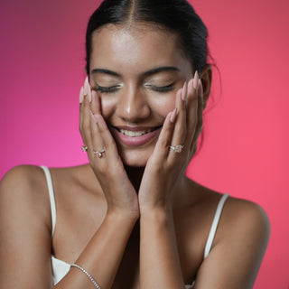 Angled top view of Reia Rose Halo Radiant Diamond Ring on a peach background with soft rose petals, highlighting the blush pink radiant-cut centre stone and halo of EF VVS diamonds.