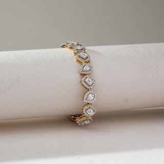 Top view of Multi Shape Diamond Bracelet in 14KT Dual Gold, featuring alternating emerald and pear-shaped lab grown diamonds with halo settings. Placed on a beige backdrop, the design highlights varied brilliance and elegance.

