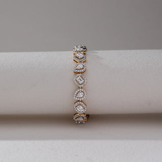 Front view of Multi Shape Diamond Bracelet in 14KT Dual Gold, featuring alternating emerald and pear-shaped lab grown diamonds with halo settings. Set on a beige backdrop, the design highlights symmetry and brilliance.
