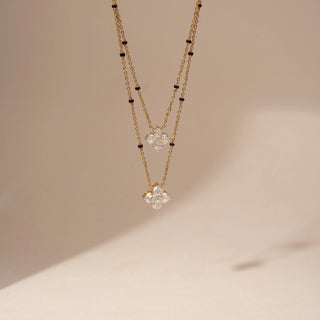 Front view of a 14KT Yellow Gold diamond necklace with two layered chains, black bead accents and two clustered diamond pendants.