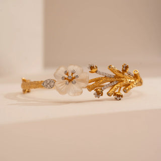 Front view of Reia’s 14 KT Yellow Gold Floral Carved Shell Diamond Bracelet. It features a frosted carved shell blossom centred on an organic, diamond-set branch motif.