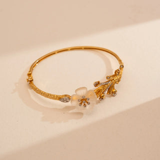 Top view of Reia’s 14 KT Yellow Gold Floral Carved Shell Diamond Bracelet. Captured on a cream backdrop, it highlights the carved shell blossom and diamond-set organic branch motif.