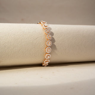 Side view of a diamond halo station bracelet in 14 KT Rose Gold, featuring cushion-shaped lab-grown diamonds framed by sparkling halo settings with elevated profiles, displayed on a beige surface.