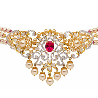 A zoomed-in view of the centrepiece of the female necklace of size 16 secured with a spring lock , on a white background, showcasing a 14 KT yellow gold choker necklace made of lab-grown white pearls features a centrepiece with a striking red Ruby with a total weight of 20.77 grams surrounded by diamond studded intrinsic lattice work with a total of 3.8 carats finished with hanging pearl drops making it a luxurious statement piece.