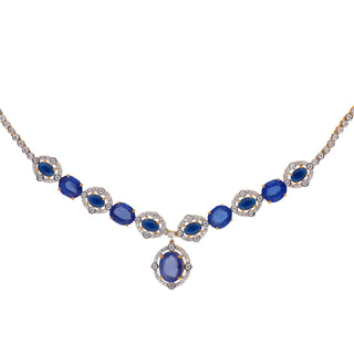 A front-side view of the female necklace of size 16, on a white background, showcasing a 14 KT yellow gold necklace secured with a spring lock featuring a symmetrical pattern of lab-grown blue Sapphires with a total product weight of 29.406 grams in a diamond-studded setting with a total of 2.37 carat finished with a central blue Sapphire hanging at the bottom creating a classy look for any occasion.