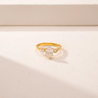Close-up view of 14KT Yellow Gold ring featuring a oval-cut centre diamond, round diamond accents and a twisted band design.