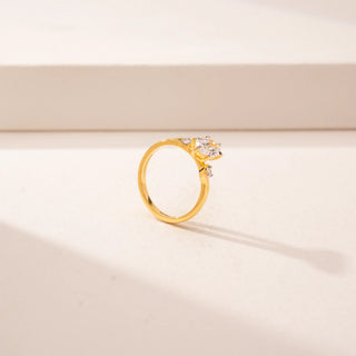 Angled view of 14KT Yellow Gold ring featuring a oval-cut centre diamond, round diamond accents and a twisted band design.