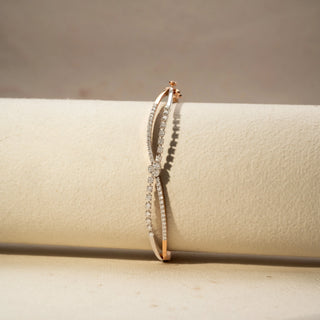 Front view of a yellow gold lab-grown diamond open bangle featuring twin pavé diamond bands with a round diamond centre, displayed on a neutral jewellery cushion.