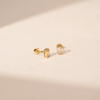 Angled view of Emerald Cut Diamond Stud Earrings in 14KT Yellow Gold, featuring rectangular lab-grown diamonds in bezel settings.