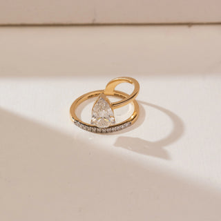 Top view of Floating Pear Bypass Diamond Ring in yellow gold, featuring a pear-shaped lab-grown diamond set within an open bypass band with pavé diamond accents, displayed on a soft beige backdrop.