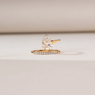 Front view of Floating Pear Bypass Diamond Ring in yellow gold, featuring a pear-shaped lab-grown diamond set in an open bypass design with pavé diamond accents, displayed on a soft beige surface.