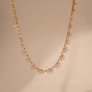 Front view of a floral lab-grown diamond necklace in 18KT Rose Gold, featuring marquise and pear-shaped diamond clusters in a continuous design. Captured against a beige backdrop, the elegant silhouette radiates brilliance.