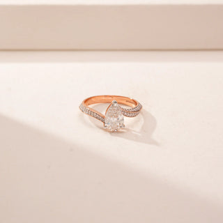 Close-up view of a 14KT Rose Gold diamond ring featuring a pear-cut centre diamond and a split pavé band.