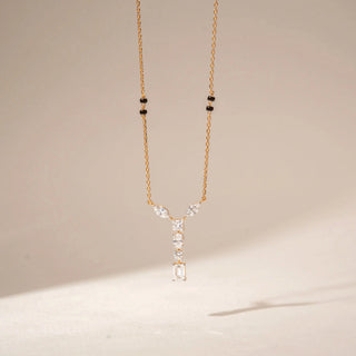 Front view of 14KT Yellow Gold mangalsutra with marquise, emerald, princess and oval-cut diamonds in a Y-shaped pendant and black beads.