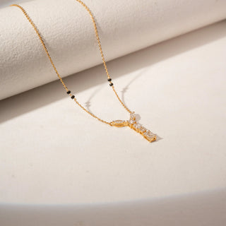 Angled view of 14KT Yellow Gold mangalsutra with marquise, Emerald, princess and oval-cut diamonds in a Y-shaped pendant and black beads.