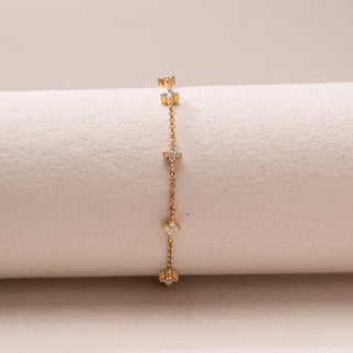 Front view of a delicate gold chain bracelet, featuring floral diamond accents spaced along the chain. Captured against a soft beige backdrop, the design reflects minimal elegance and refined sparkle.
