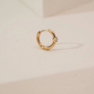 Side angled view of Minimalist Round Solitaire Diamond Nosepin in yellow gold, highlighting a single round lab-grown diamond set in a classic solitaire design on a neutral surface.