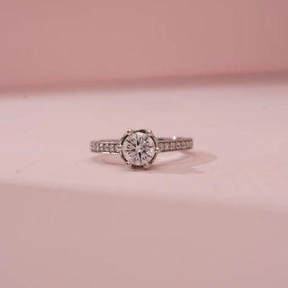 Front view of Reia’s 14 KT White Gold Pure Brilliance Diamond Solitaire Ring. Captured against a pink backdrop, it highlights the magnificent round brilliant-cut centre stone.