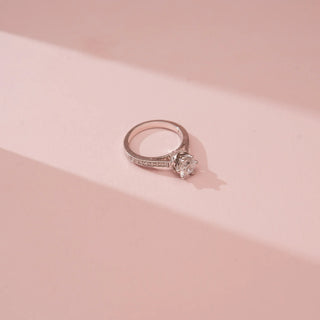 Angled top view of Reia’s 14 KT White Gold Pure Brilliance Diamond Solitaire Ring. Captured against a pink backdrop, the layout highlights the majestic presence and breathtaking trail of light.