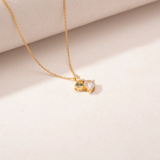 Top view of a 14KT Yellow Gold diamond pendant featuring a green heart-shaped diamond and a pear-shaped diamond charm.