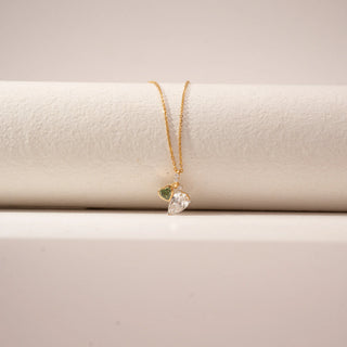 Close-up view of a 14KT Yellow Gold diamond pendant featuring a green heart-shaped diamond and a pear-shaped diamond charm.
