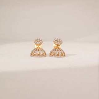 Angled view of floral lab-grown diamond jhumka earrings in 18KT Yellow Gold, featuring marquise diamond flower studs with openwork dome drops. Captured against a beige backdrop, the intricate design showcases fine craftsmanship.