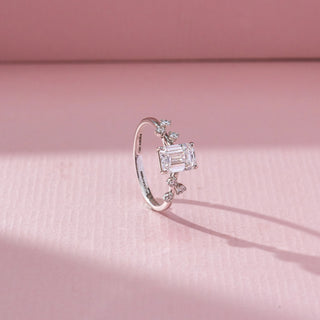 Side view of Emerald Cut Solitaire Diamond Ring in 14KT White Gold, featuring a centred emerald-cut lab grown diamond with leaf-like accents. Set on a pink backdrop, the design highlights structure and elegance.

