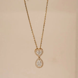 Front view of heart and teardrop diamond pendant in yellow gold, featuring pavé round lab grown diamonds with a pear-shaped centre stone, suspended on a delicate chain against a soft neutral backdrop.
