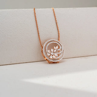 Close-up view of a rose gold floral pendant necklace with diamond-studded spiral circles and marquise-cut diamond flower accents, displayed against a soft cream-colored backdrop.