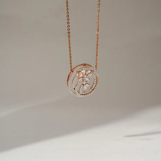 Side view of a rose gold floral pendant necklace with diamond-studded spiral circles and marquise-cut diamond accents, highlighting the layered openwork design on a soft cream background.