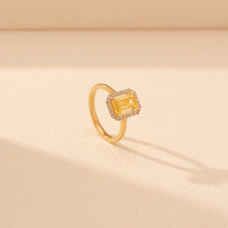 Angled view of Emerald-Cut Yellow Diamond Halo Ring in 14KT Yellow Gold, featuring a yellow emerald-cut diamond with a pavé halo.