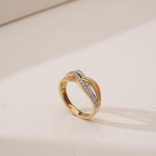 Angled view of Golden Infinity Twist Diamond Band in yellow gold, showcasing interwoven gold ribbons with pavé-set round lab-grown diamonds forming a flowing infinity-inspired design on a neutral background.
