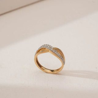 Side angled view of Golden Infinity Twist Diamond Band in yellow gold, showcasing interwoven gold ribbons with pavé-set round lab-grown diamonds forming a flowing infinity design on a neutral surface.