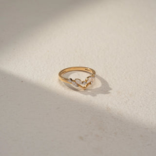 Top view of a chevron diamond band in 14 KT Yellow Gold, featuring marquise-cut and round lab-grown diamonds arranged in a delicate leaf-inspired V-shaped design, displayed against a beige backdrop.