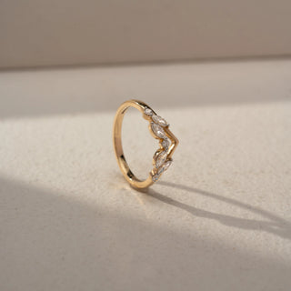 Angled view of a chevron diamond band in 14 KT Yellow Gold, featuring marquise-cut and round lab-grown diamonds arranged in a delicate leaf-inspired V-shaped design, displayed against a beige backdrop.