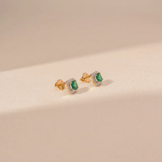Side view of 14KT yellow gold square green gemstone stud earrings, framed by a sparkling diamond halo.