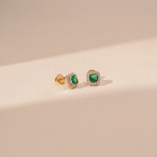 Angled view of 14KT yellow gold square green gemstone stud earrings, framed by a sparkling diamond halo.