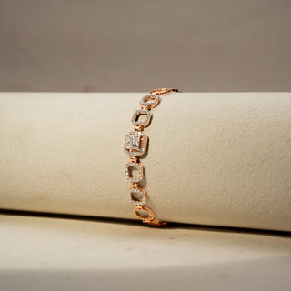 Close up view of a diamond bracelet in 14 KT Rose Gold, featuring repeating circular pavé-set diamond motifs linked in a graceful linear design, displayed against a soft beige backdrop.
