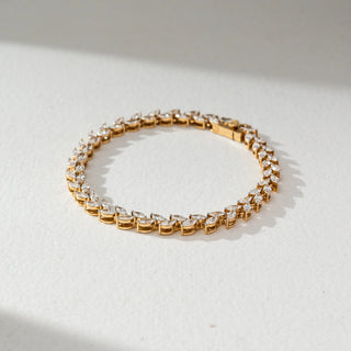 Angled view of Marquise Diamond Tennis Bracelet in 14KT Yellow Gold, featuring a continuous row of marquise-shaped lab grown diamonds in prong setting. Set on a neutral backdrop, the design highlights fluid brilliance and elegance.
