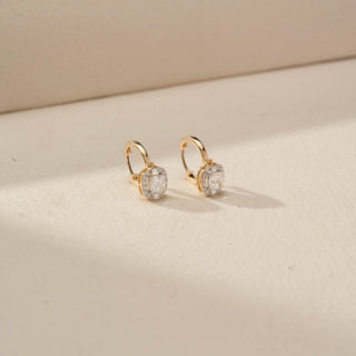 Angled front view of cushion halo drop earrings in 14 KT Yellow Gold, featuring cushion-cut lab-grown diamonds framed by sparkling halo settings, suspended from sleek huggie hoops on a beige backdrop.