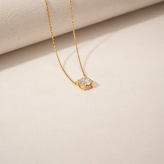 Top view of a round diamond pendant in 14KT Yellow Gold, featuring a solitaire stone in a delicate setting against a beige backdrop.