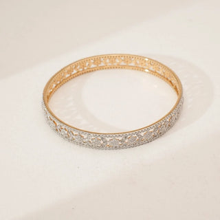 Top view of intricate leaf cluster diamond bangle featuring detailed openwork floral motifs and pavé-set lab-grown diamonds along the band, displayed on a soft neutral surface.