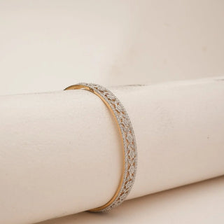 Angled side view of intricate leaf cluster diamond bangle with delicate openwork floral motifs and pavé-set lab-grown diamonds along the border, displayed on a soft beige cylindrical stand.