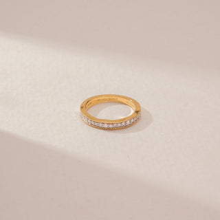 Top view of a diamond eternity band in 14KT Yellow Gold, featuring a continuous row of round diamonds with beaded gold edges on a beige backdrop.