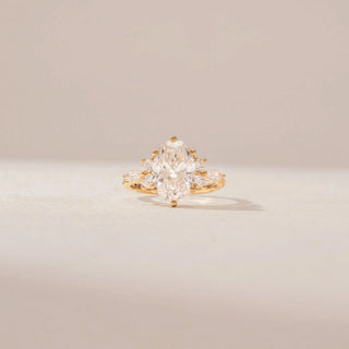 Front view of a 14KT Yellow Gold diamond ring featuring an oval centre diamond, marquise and round diamond accents, and a prong setting.
