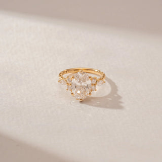Close-up view of a 14KT Yellow Gold diamond ring featuring an oval centre diamond, marquise and round diamond accents, and a prong setting.